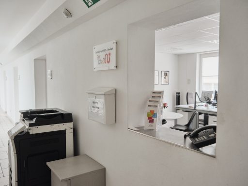 Heller Büroraum mit mehreren Arbeitsplätzen und einem Empfangsbereich.