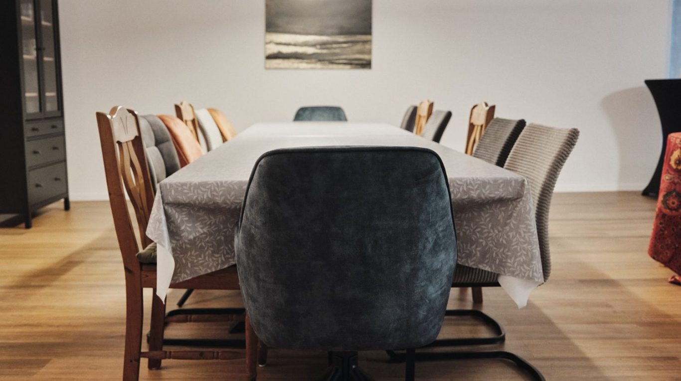 Tafel mit dem Schriftzug „Wir sind die Guten“ und drei Tassen auf einem Tisch.
